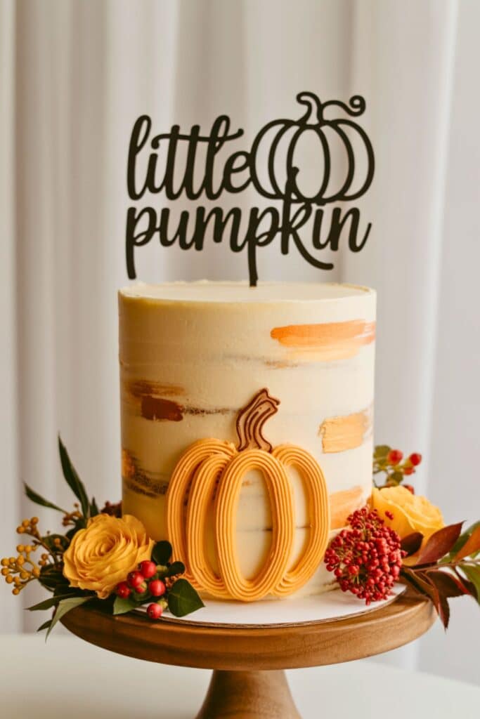 Little Pumpkin baby shower cake with a minimalist buttercream design, pumpkin-shaped piping, fresh floral accents, and a black acrylic cake topper that reads ‘Little Pumpkin’—a simple and elegant fall-themed baby shower cake.