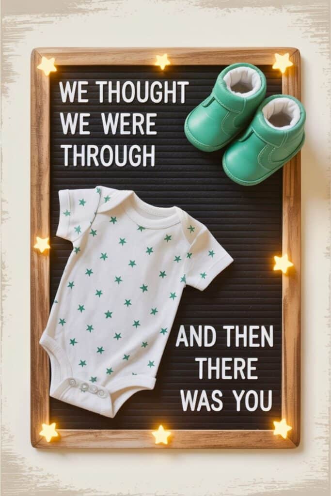 Unexpected pregnancy announcement with letterboard that reads ‘We thought we were through… and then there was you,’ displayed with baby onesie and green baby shoes.