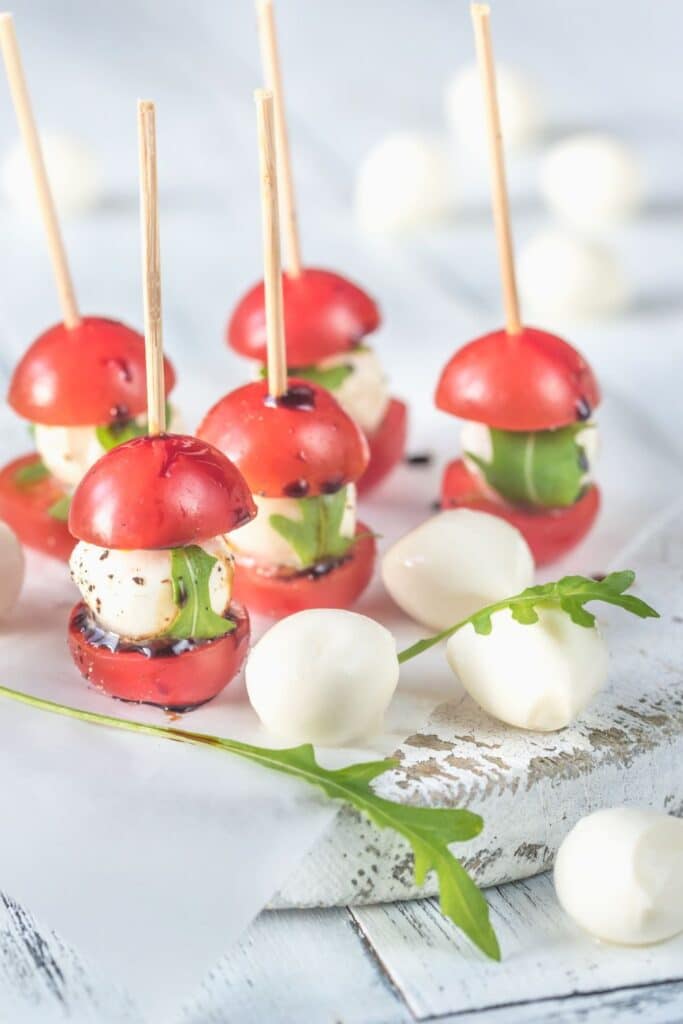 Mini caprese skewers made with cherry tomatoes, mozzarella balls, basil, and balsamic glaze on toothpicks. An easy, colorful appetizer idea perfect for baby showers, birthday parties, or summer entertaining.