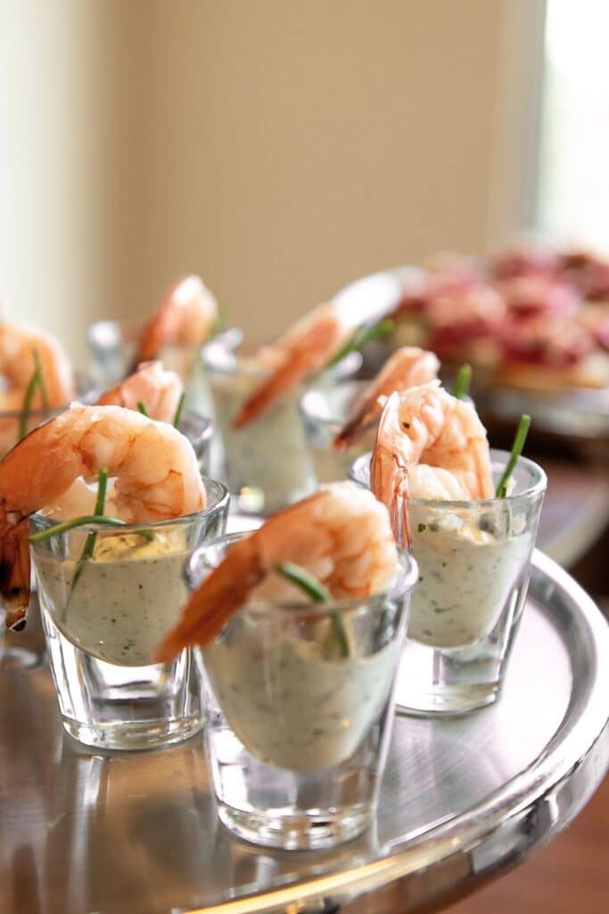 Shrimp cocktail appetizers served in individual shot glasses with creamy dipping sauce and garnished with fresh herbs. A classy and easy party appetizer perfect for baby showers, brunches, or elegant birthday parties.