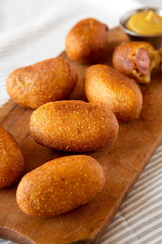 Golden brown mini corn dogs served on a wooden board with mustard dipping sauce. A nostalgic, kid-friendly party appetizer that’s perfect for birthday parties, baby showers, or casual gatherings.