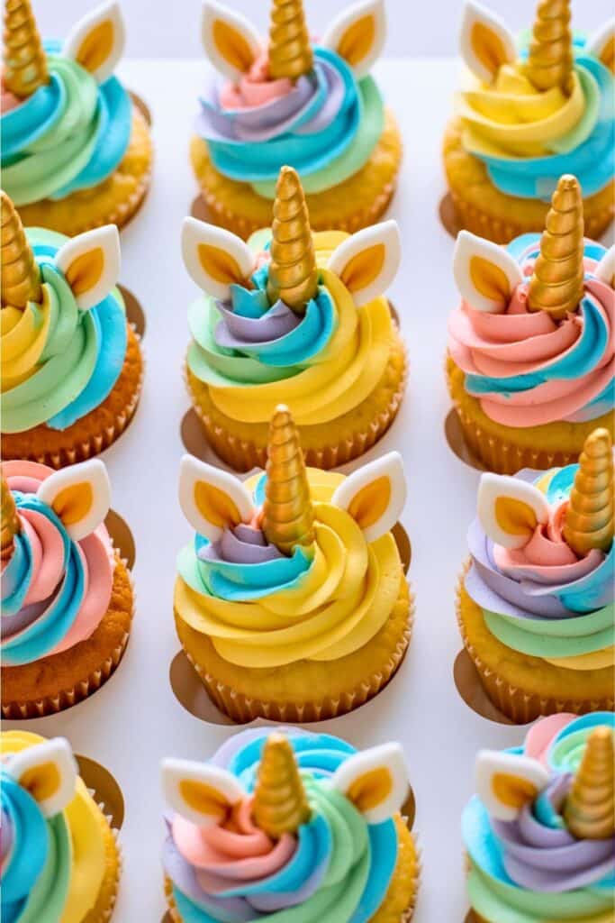 Colorful unicorn cupcakes with swirls of pastel frosting, gold fondant horns, and edible unicorn ears — a magical dessert idea for a unicorn birthday party or themed celebration.