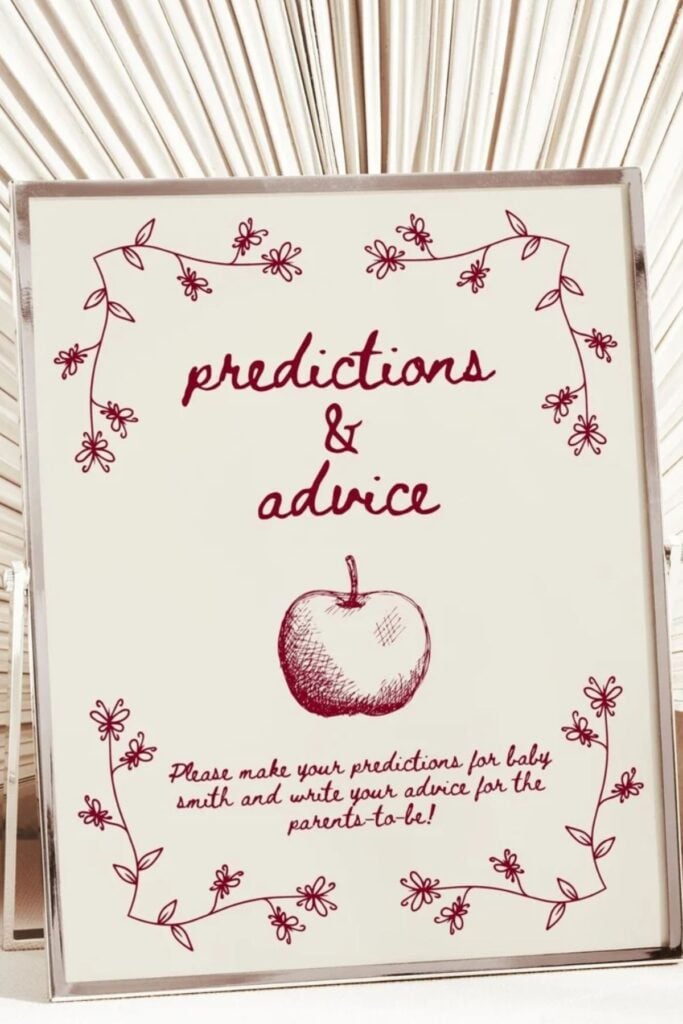 Apple of My Eye baby shower predictions and advice sign with red apple illustration and floral border — fall baby shower game station idea.