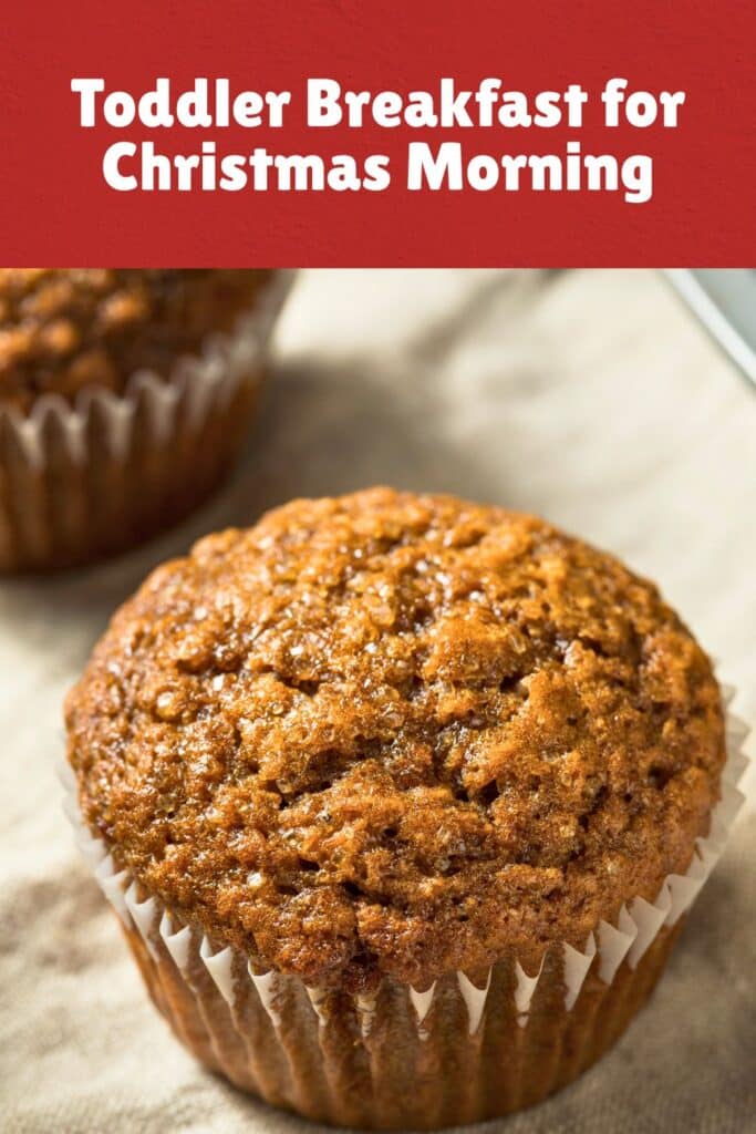 A close-up of a freshly baked gingerbread muffin on a linen napkin, with a second muffin blurred in the background. This cozy and spiced toddler Christmas breakfast idea is a quick and comforting option for a festive holiday morning.