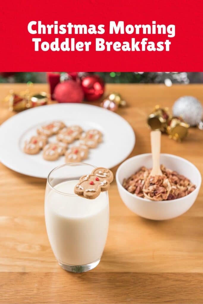 A glass of milk with a gingerbread man cookie perched on the rim, next to a bowl of granola and a plate of mini gingerbread cookies in the background. This simple and festive toddler Christmas breakfast idea is easy, cheerful, and perfect for a cozy holiday morning.