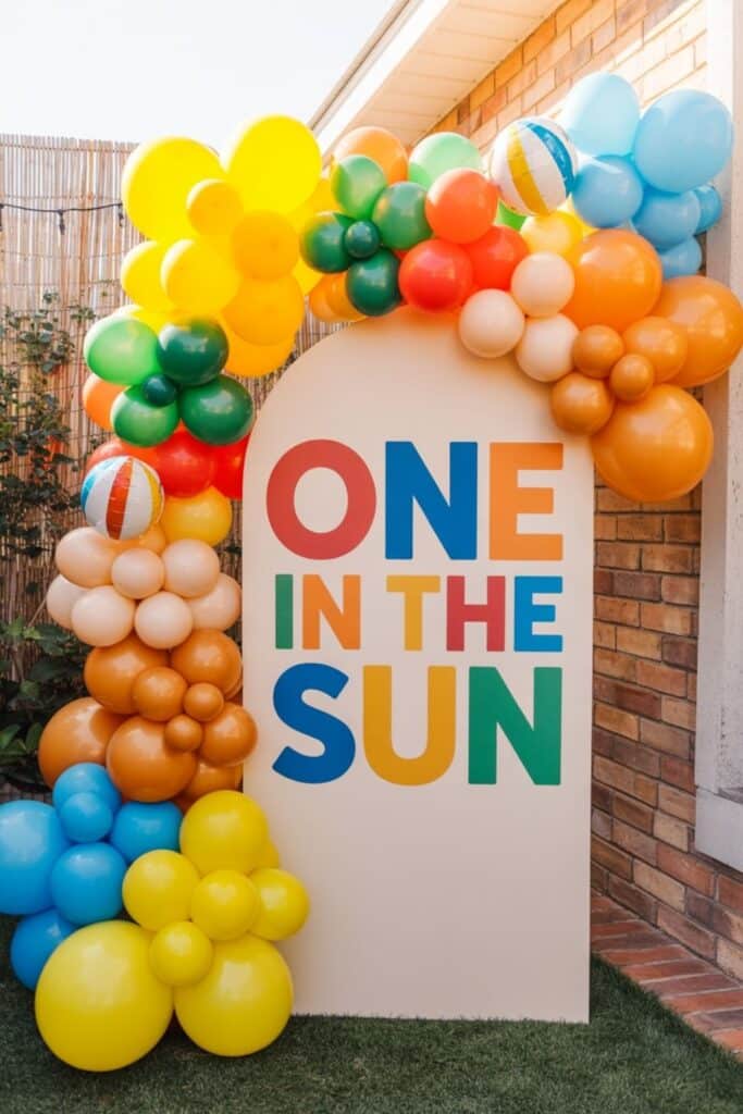 One in the Sun first birthday decor with a bright balloon arch and large statement sign, ideal for a summer first birthday party, outdoor birthday celebration, sunshine theme party ideas, and first birthday theme ideas for boys