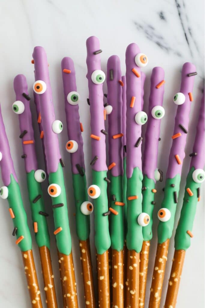 monster themed pretzel rods with green chocolate and candy eyes for a we’ve created a monster baby shower food idea